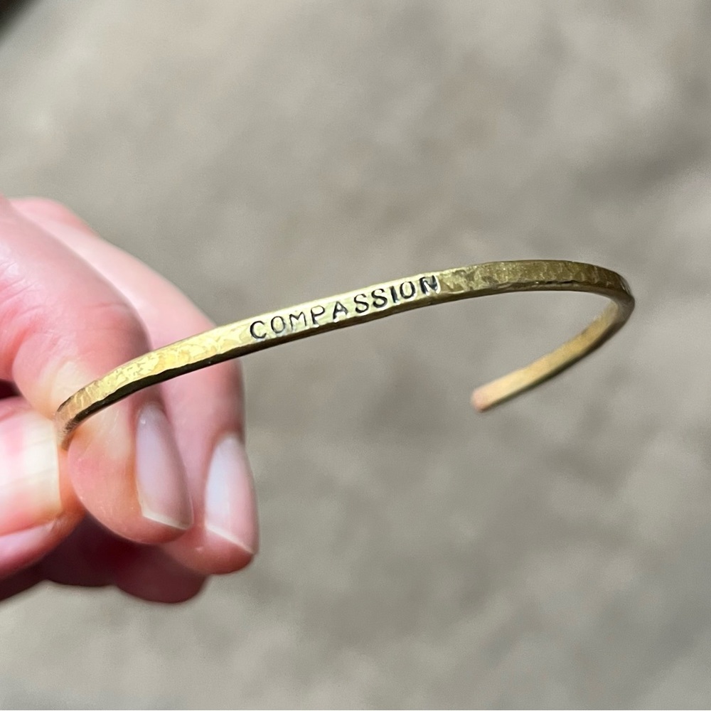 Brass bangle with “Compassion” stamped on it. Hammered finish.